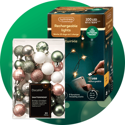 Verpackung mit 33 kugelförmigen Weihnachtsbaumkugeln in Grün-, Rosa-, Weiß- und Metallic-Tönen neben einer Kartonverpackung für wiederaufladbare Lichterkette „lumineo Rechargeable lights 100 LED“ mit Hinweis „USB rechargeable“ und „No more batteries needed“