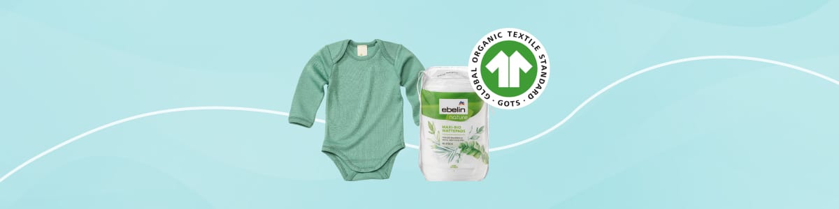 grün melierter Baby-Body mit langen Ärmeln neben verpackter Windelpackung der Marke „ebbio“ mit Bio-GOTS-Logo auf hellblauem Hintergrund