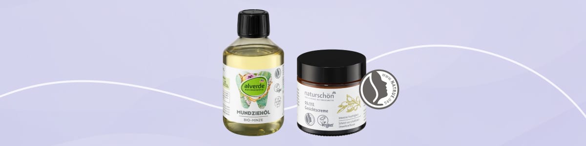 Zwei Naturkosmetikprodukte vor lila Hintergrund: links eine transparente Flasche mit gelblicher Flüssigkeit und Etikett „alverde MUNDSPÜLUNG“, schwarzer Schraubverschluss, rechts ein rundes schwarzes Döschen mit Aufschrift „naturschön“ und Bild einer Vanilleschote sowie Siegelsymbol