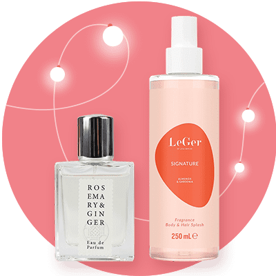 Zwei Parfümflaschen vor einem rosa Hintergrund mit weißen Lichtpunkten, links eine quadratische Flasche mit der Aufschrift „Rosemary & Ginger“, rechts eine zylindrische Flasche mit der Aufschrift „LeGer Signature Fragrance Body & Hair Splash“