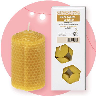 Eine zylindrische Kerze aus gelbem Bienenwachs mit Wabenstruktur neben einer Verpackung mit der Aufschrift „Bienenwachs-Teelichter Handarbeit 100% reines Bienenwachs Hergestellt im Schwarzwald 10 Stück“