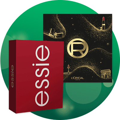 Rotes Geschenkpaket mit weißem Marken Schriftzug „essie“ neben schwarzer, goldakzentuierter L’Oréal-Geschenkbox mit goldenem Kreislogo und kleinen Illustrationen (Lippenstift, Gebäude) vor grünem Kreishintergrund