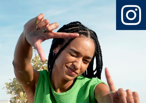 Eine Person mit geflochtenen Haaren trägt ein grünes Oberteil und formt mit den Händen ein Rechteck, oben rechts das Instagram-Logo
