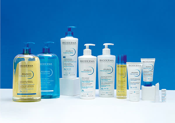 Mehrere Bioderma Pflegeprodukte stehen vor einem blauen Hintergrund, darunter Flaschen und Tuben mit Aufschriften wie „Atoderm“ und „Crème Ultra“