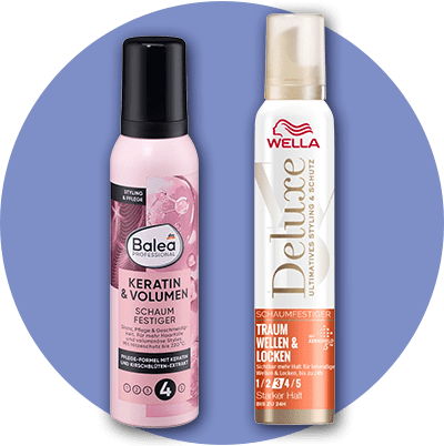 Zwei Flaschen Schaumfestiger nebeneinander. Links eine rosa Flasche von Balea Professional mit der Aufschrift „Keratin & Volumen Schaumfestiger“. Rechts eine weiße Flasche von Wella Deluxe mit der Aufschrift „Traum Wellen & Locken“.