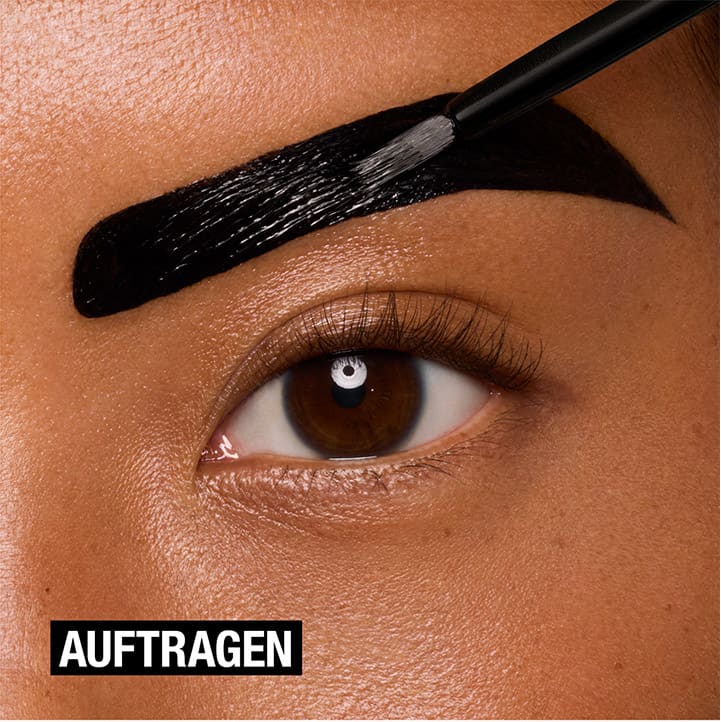 Ein Auge mit einem Pinsel, der schwarze Farbe auf die Augenbraue aufträgt