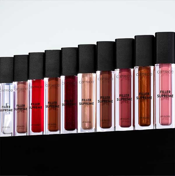 Eine Reihe von Catrice Filler Supreme Lipgloss in verschiedenen Farben, darunter Rot, Braun und Rosa, in transparenten Flaschen mit schwarzem Deckel