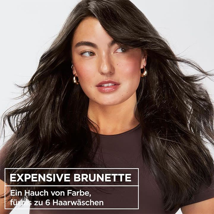 Eine Person mit langen, dunklen Haaren trägt ein dunkelgraues Oberteil. Unten im Bild steht der Text „EXPENSIVE BRUNETTE“.
