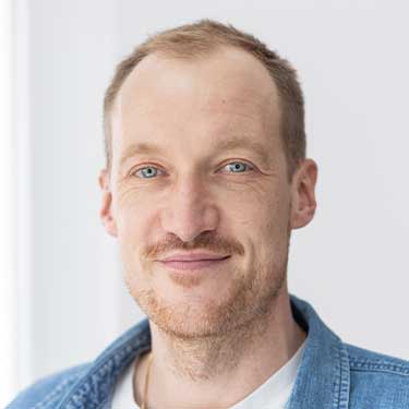 Porträt der erwachsenen Person Konstantin Wagner von den Schultern aufwärts mit kurzem hellbraunem Haar, hellblauem Hemdkragen sichtbar und neutralem Gesichtsausdruck vor hellem Hintergrund
