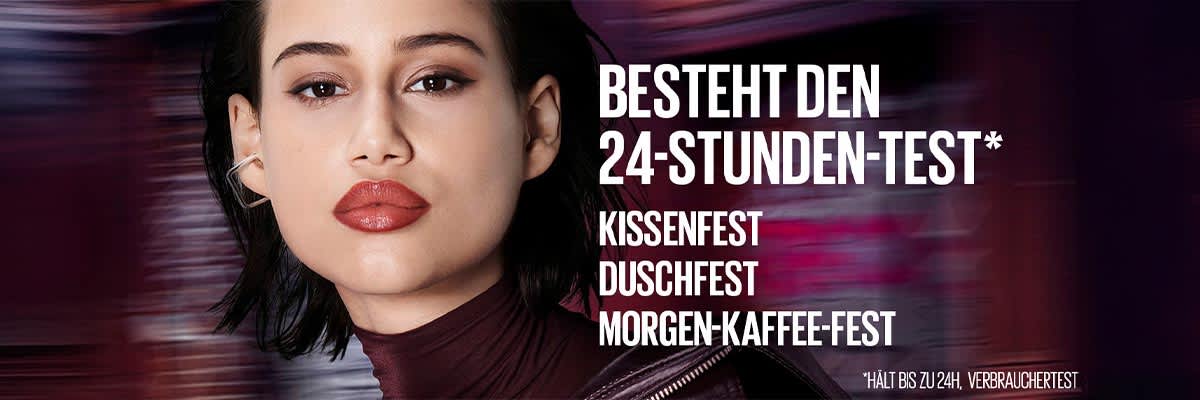 Frau mit dunklen Haaren und rotem Lippenstift neben weißer Textleiste „BESTEHT DEN 24‑STUNDEN‑TEST*“ und darunter die Auflistung „KISSENFEST DUSCHFEST MORGEN‑KAFFEE‑FEST“ auf dunklem Hintergrund
