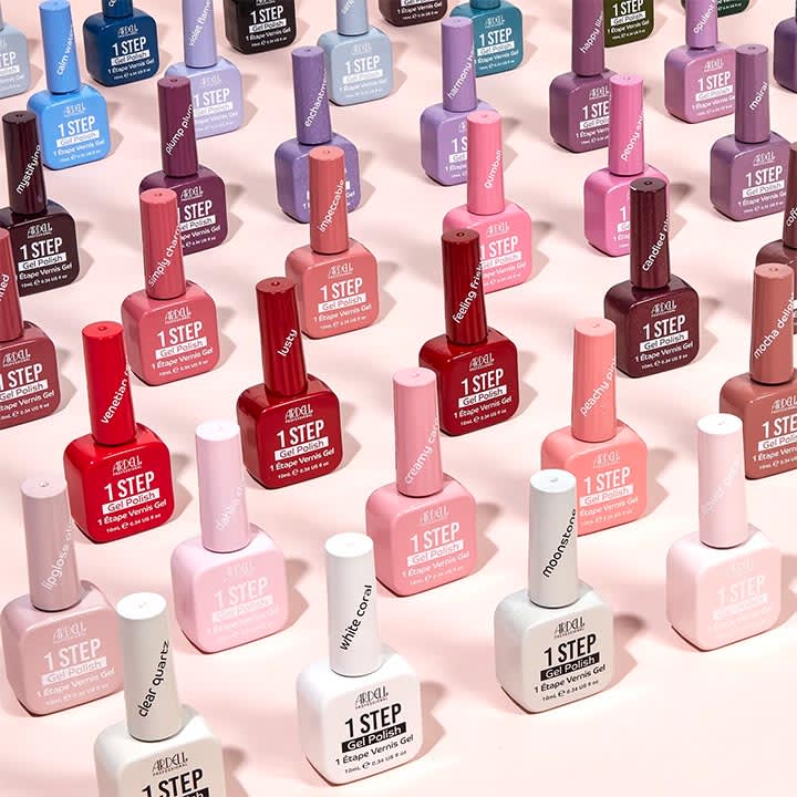 Mehrere Reihen bunter Nagellack-Fläschchen der Marke ARDELL mit der Aufschrift „1 STEP“ in verschiedenen Rosé-, Rot-, Blau- und Nude-Tönen auf hellrosa Hintergrund