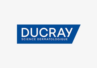 Logo von Ducray in weißer Großschrift auf blauem trapezförmigem Hintergrund mit dem Zusatztext „SCIENCE DERMATOLOGIQUE“ in Großbuchstaben darunter