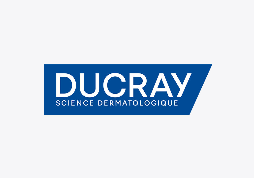Logo der Marke Ducray in weißer Schrift auf blauem, nach rechts spitz zulaufendem Banner mit dem Zusatztext „SCIENCE DERMATOLOGIQUE“