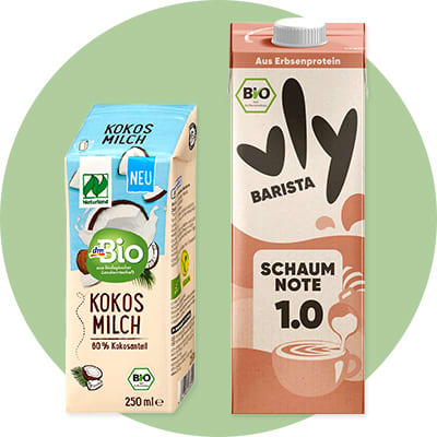 Zwei Getränkepackungen vor grünem Kreis: links dmBio Kokosmilch 250 ml, rechts Vly Barista Haferdrink „Schaumnote 1.0“ in Tetra Pak