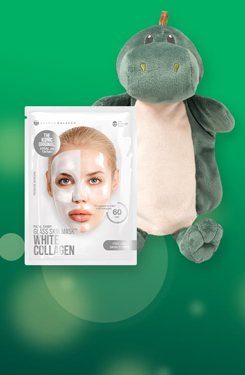 Plüschdinosaurier in grün mit hellem Bauch liegt neben einer weißen Gesichtsmaske-Verpackung mit Frauenporträt und Aufschrift „Glass Skin Mask White Collagen“