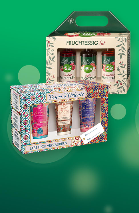 Zwei Geschenksets: oben ein helles Kartonträger-Set mit drei Flaschen Bio-Fruchtessig (Sorten sichtbar) mit Aufschrift „FRUCHTESSIG Set“, unten ein bunt gemustertes Tesori d'Oriente-Set mit drei Dusch- oder Körperpflege-Proben und Schriftzug „Tesori d'Oriente“ und „LASS DICH VERZAubern“