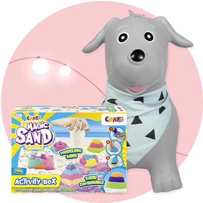 Ein grauer Hund mit einem hellblauen Halstuch, das schwarze Dreiecke zeigt, steht neben einer Verpackung von Magic Sand Modelliersand mit bunten Sandformen und der Aufschrift „Magic Sand“