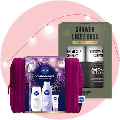 Zwei Produktverpackungen vor einem rosa Hintergrund mit Lichterkette. Links eine lila Nivea Geschenkbox mit der Aufschrift „Wegbegleiter Moments of Joy“ und drei Nivea-Produkten. Rechts eine Brooklyn Soap Company Geschenkbox mit der Aufschrift „Shower Like a Boss“ und zwei Duschgels mit den Düften „Oud Wood & Sandal“