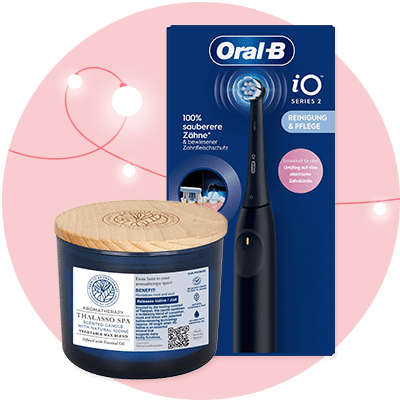 Eine schwarze elektrische Zahnbürste mit blauem Licht und der Aufschrift „iO Series 2“ steht vor einer Verpackung mit der Aufschrift „100% sauberere Zähne & besserer Zahfleischschutz“. Daneben eine dunkelblaue Kerze mit Holzdeckel und Aufschrift „Aromatherapy Thalasso Spa Scented Candle“