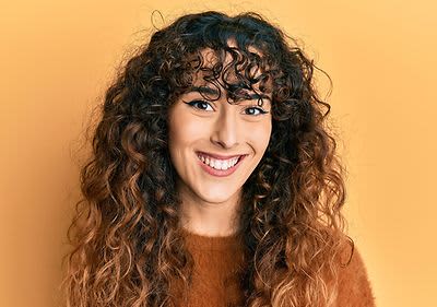 Frau mit lockigem Haar vor gelber Wand