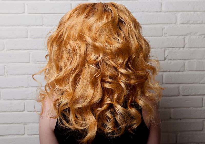 Lockiges rotes Haar vor weißer Wand