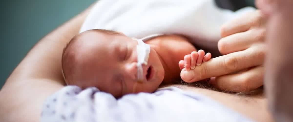 Frühchen hält die Hand eines Erwachsenen