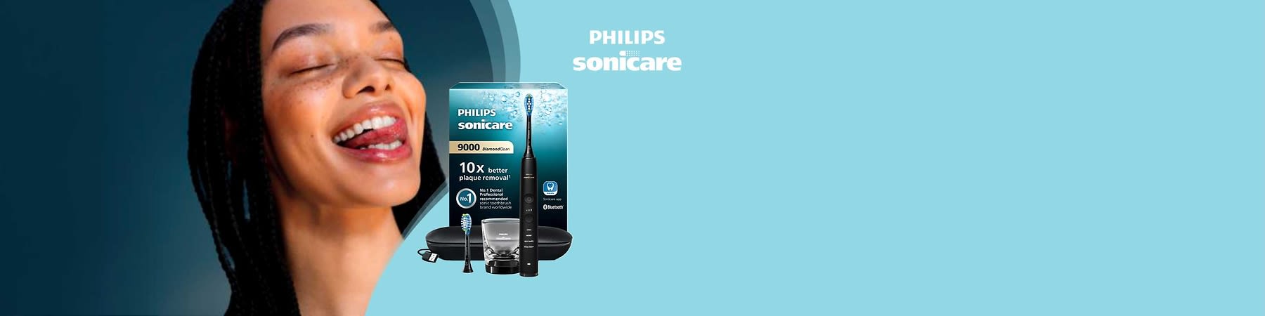 Packung und Zubehör einer schwarzen Philips Sonicare 9000 DiamondClean Schallzahnbürste vor hellblauem Hintergrund, links die Produktverpackung mit Aufschrift „Philips Sonicare 9000 DiamondClean“ und dem Hinweis „10x better plaque removal“, mittig eine schwarze Handzahnbürste mit aufgesetztem Bürstenkopf, darunter ein Ersatzbürstenkopf, eine transparente Ladeschale, ein USB-Ladekabel und ein schwarzes Reiseetui, rechts oben das weiße Philips Sonicare Logo