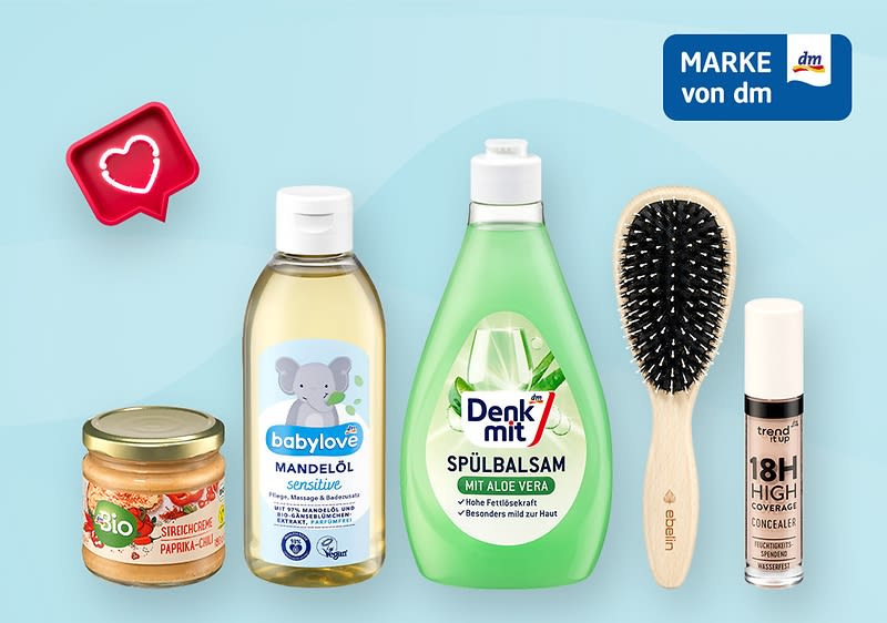 Eine Collage mit sechs Produkten von dm: Links oben ein rotes Herzsymbol, darunter ein Glas Bio-Süßcreme mit Paprika und Cashew, daneben eine Flasche babylove Mandelöl sensitive mit Elefantenmotiv, in der Mitte eine grüne Flasche Denk mit Spülbalsam mit Aloe Vera, rechts eine schwarze Haarbürste mit Holzgriff, ganz rechts ein trend IT UP 18H High Coverage Concealer