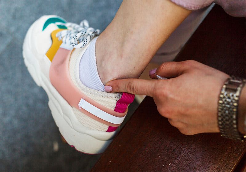 Ein Finger zeigt auf eine Stelle am Knöchel, wo der Schuh reibt.