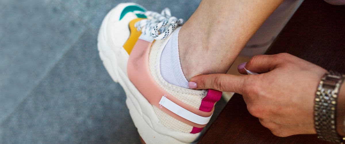 Ein Finger zeigt auf eine Stelle am Knöchel, wo der Schuh reibt.