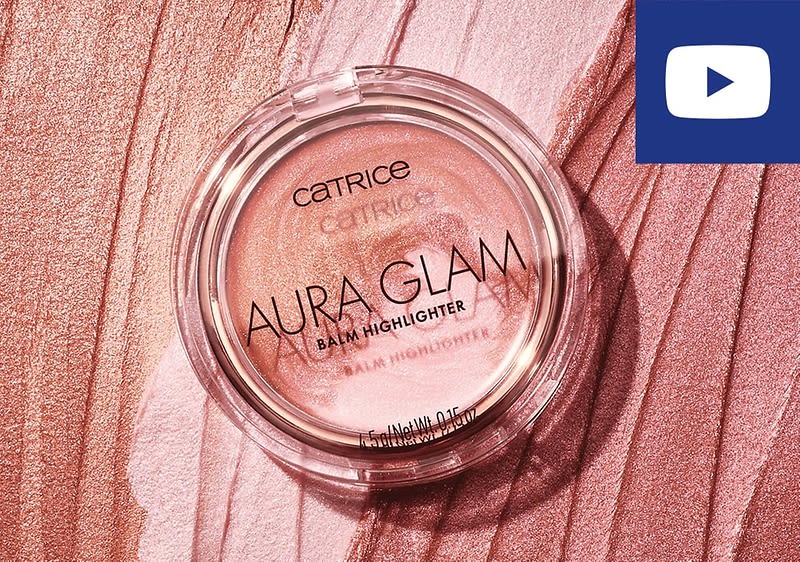 Eine runde, transparente Verpackung mit einem rosafarbenen Highlighter von Catrice, auf der die Aufschrift Catrice Aura Glam Balm Highlighter und Balm Highlighter zu sehen ist, liegt auf einer rosafarbenen, strukturierten Oberfläche; oben rechts befindet sich ein blaues Rechteck mit einem weißen Play-Symbol, das an das YouTube-Logo erinnert.