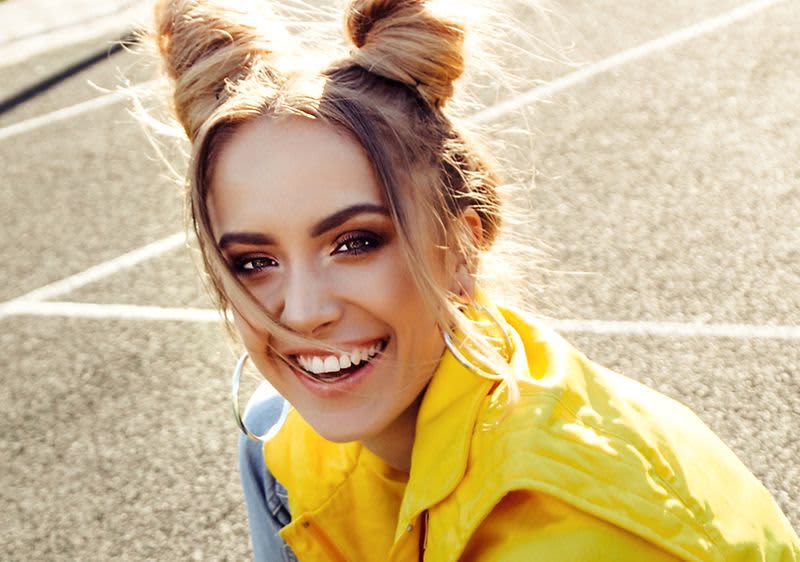 Frau mit 90er-Make-up-Look und Creolen sowie passenden Produkten