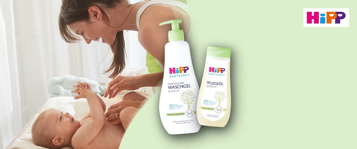 Zwei Produktverpackungen von HiPP, links ein weißes Waschgel mit grünem Pumpspender und der Aufschrift „Sanft und pur Waschgel Sensitiv“, rechts ein weißes Pflegeöl mit grünem Deckel und der Aufschrift „Pflegeöl Sensitiv“, beide mit einem Baum-Design und dem HiPP-Logo oben rechts