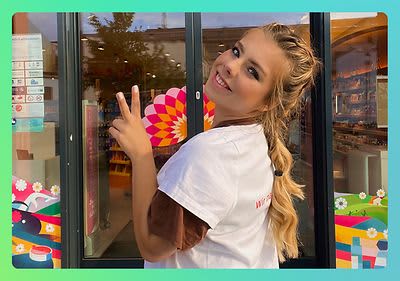 dm-Mitarbeiterin fröhlich vor dem dm-Markt Eingang