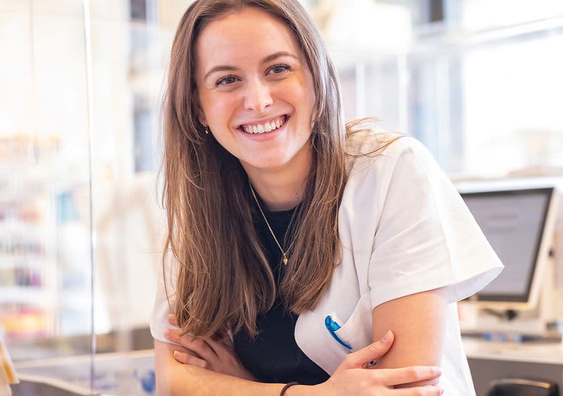 Eine lächelnde Mitarbeiterin an der Kasse eines dm-Marktes