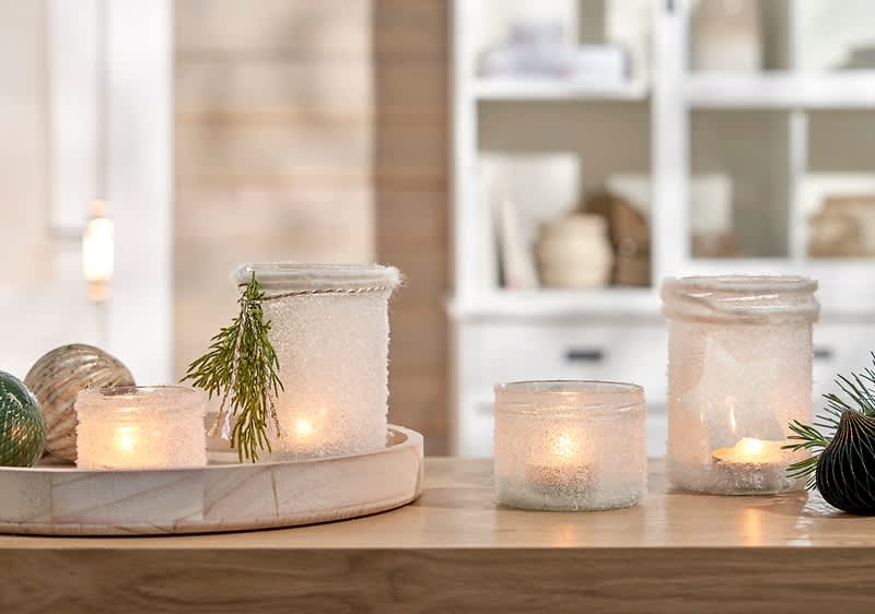 Kerzen in dekorativen Gläsern auf Tisch