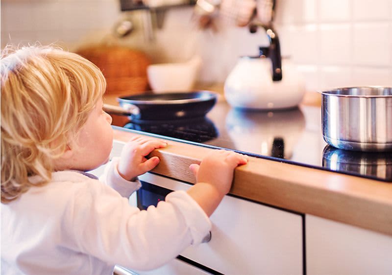 Kleinkind zieht sich am Herd hoch