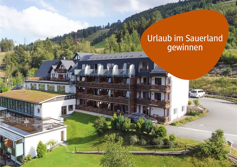 Mehrstöckiges Hotelgebäude mit Balkonen in grüner Berglandschaft, orangefarbene Sprechblase mit weißer Aufschrift „Urlaub im Sauerland gewinnen“