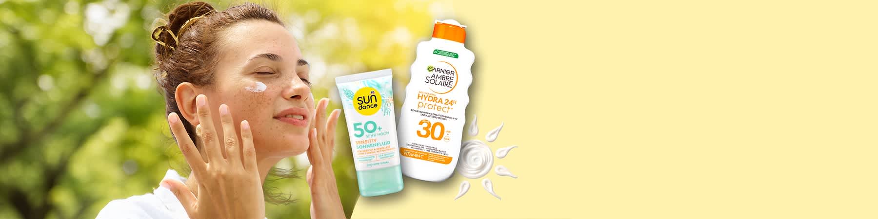 Eine Frau hält ihre Hände vor das Gesicht. Links eine Tube mit der Aufschrift „Sun Dance Sensitiv Sonnenfluid 50+ LSF“, rechts eine Flasche mit der Aufschrift „Garnier Ambre Solaire Hydra 24 Protect+ 30 LSF“. Beide Produkte sind Sonnenschutzmittel.