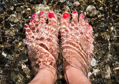 Füße im Wasser mit rotem Nagellack