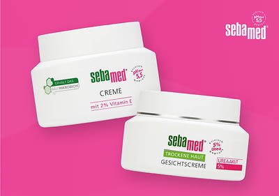 Zwei weiße Cremetiegel mit grüner und roter Aufschrift auf einem pinken Hintergrund, der linke Tiegel ist mit dem Text sebamed Creme mit 2% Vitamin E und der rechte Tiegel mit sebamed Gesichtcreme Trockene Haut Urea 5% beschriftet, oben rechts befindet sich das sebamed-Logo in Weiß