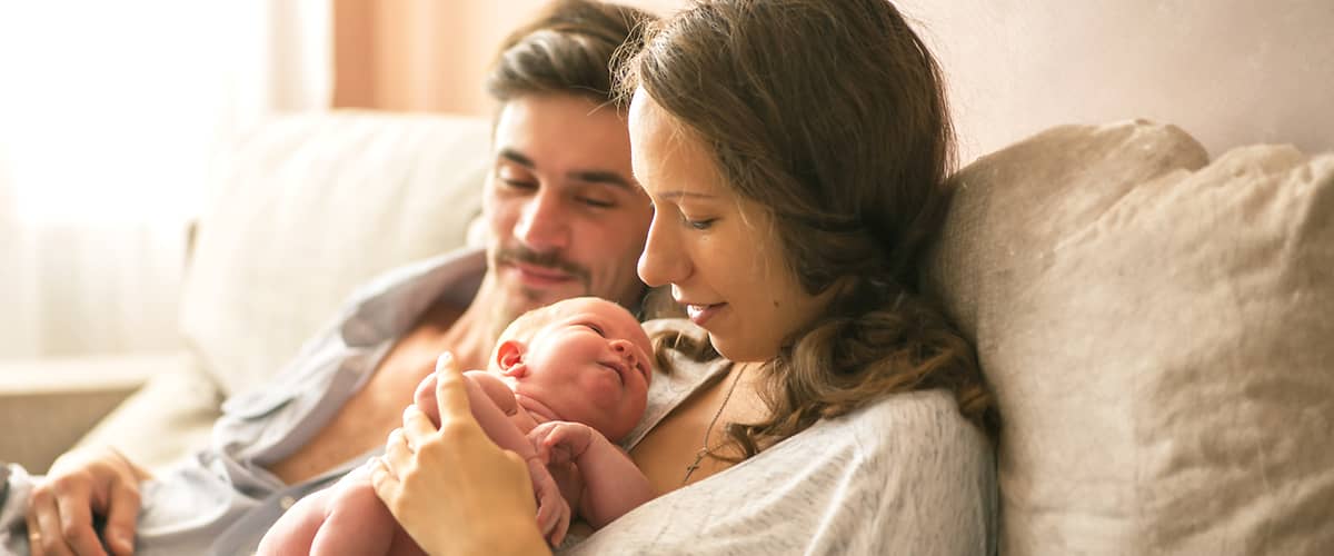 Junge Eltern mit Neugeborenem im Wochenbett