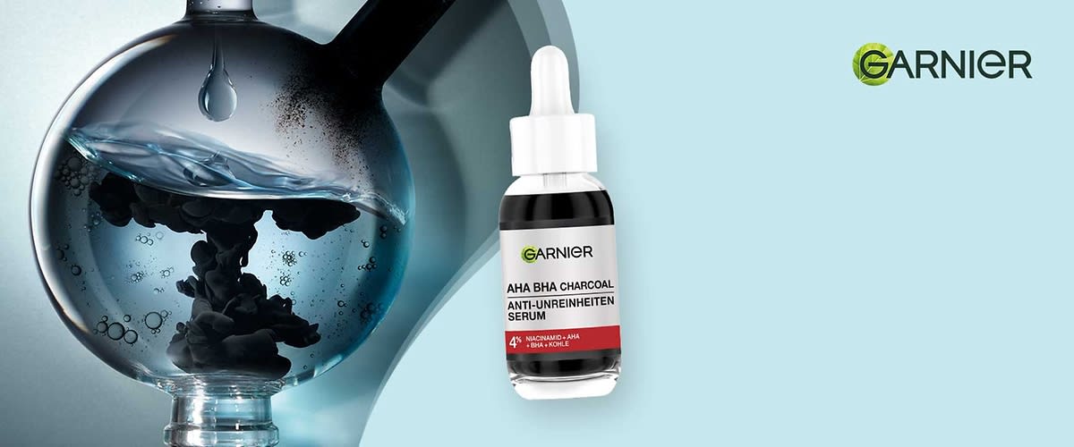 Garnier-Serumfläschchen mit Pipette, auf dem Etikett lesbar: „AHA BHA CHARCOAL ANTI-UNREINHEITEN SERUM“ und „4%“ vor hellem Hintergrund, rechts oben Garnier-Logo