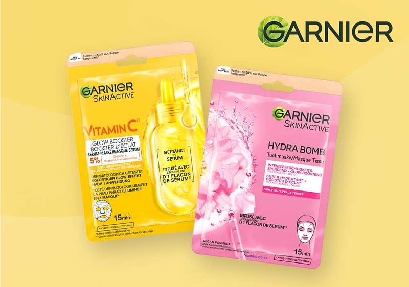 Zwei Garnier SkinActive Tuchmasken nebeneinander: links gelbe Verpackung Vitamin C Glow Booster mit Serumfläschchen-Illustration, rechts rosa Verpackung Hydra Bomb mit Wasser- und Blütenmotiv, oben rechts Garnier-Logo
