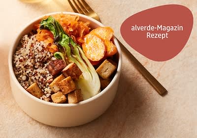 Eine Schüssel mit Quinoa, gebratenem Tofu, Pak Choi, gerösteten Karottenscheiben und geraspelten Karotten, daneben ein goldener Löffel auf einer beigen Oberfläche, oben rechts ein rotes Feld mit der Aufschrift alverde-Magazin Rezept