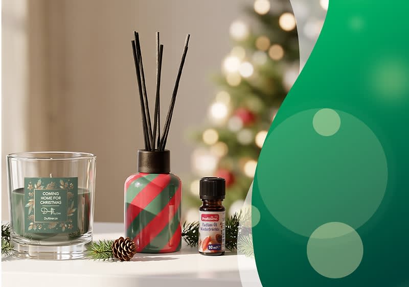 Auf einem Tisch eine Duftkerze im Glas mit grünem Etikett, daneben ein rot-grün gestreifter Diffuser mit schwarzen Stäbchen und eine kleine Flasche ätherisches Öl, im Hintergrund unscharfer Weihnachtsbaum und Tannenzweige mit Zapfen. Bild mithilfe von KI erstellt