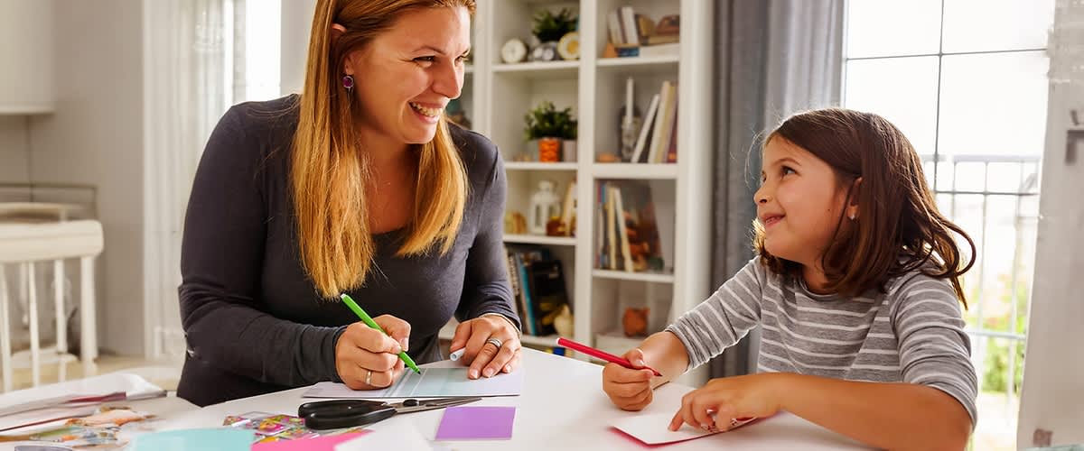 Eine Mutter bastelt mit ihrer Tochter Geburtstagseinladungen