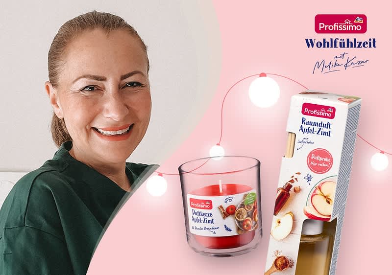 Eine rote Duftkerze im Glas mit der Aufschrift „Duftkerze Apfel-Zimt“ neben einer Verpackung mit der Aufschrift „Profissimo Raumduft Apfel-Zimt“ und Bildern von Äpfeln und Zimtstangen, im Hintergrund eine Lichterkette und das Profissimo-Logo mit dem Text „Wohlfühlzeit mit Melike Kara“