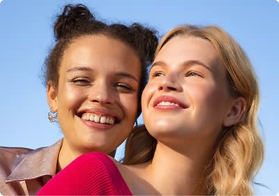 Zwei Frauen lachen in die Kamera.