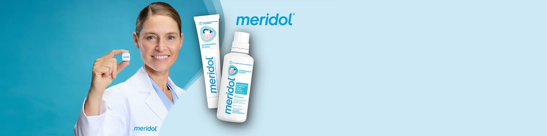 Zahncreme-Tube und Mundspülungs-Flasche der Marke meridol in weiß und türkis vor hellblauem Hintergrund, links eine Person im weißen Kittel mit meridol-Logo hält ein kleines weißes Tablettenförmiges Objekt zwischen Daumen und Zeigefinger, oben rechts das Wort „meridol“ in blau sichtbar